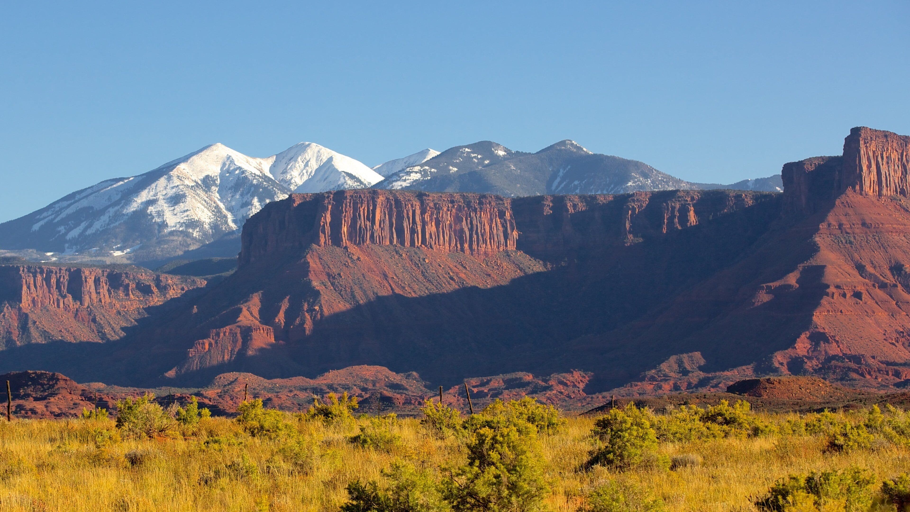 A mountain range with snow-capped peaks and red rock formations.