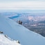 Une pente de montagne enneigée sur laquelle descendent deux skieurs.