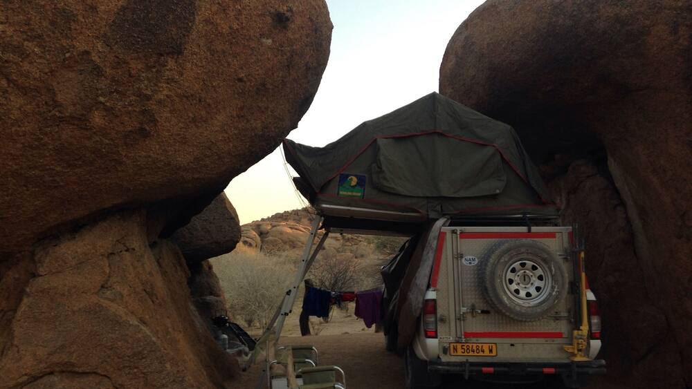 A vehicle parked in a narrow canyon with a tent set up.