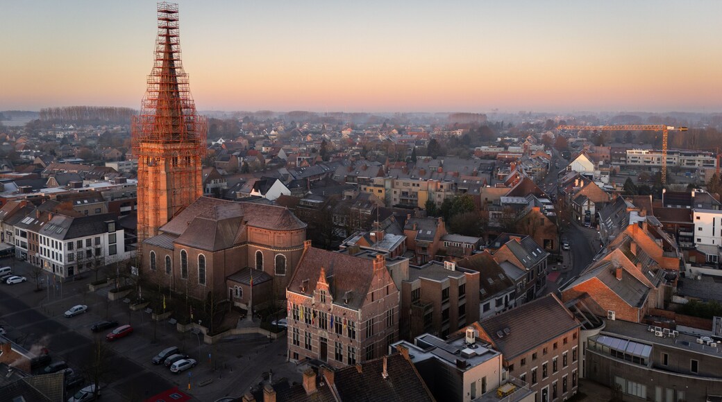 aerial view, drone view of the Sint-Servatiuskerk church in Diepenbeek, Belgium. The tower is standing in construction scaffolding for renovation of the tower. Early morning sunrise during winter.