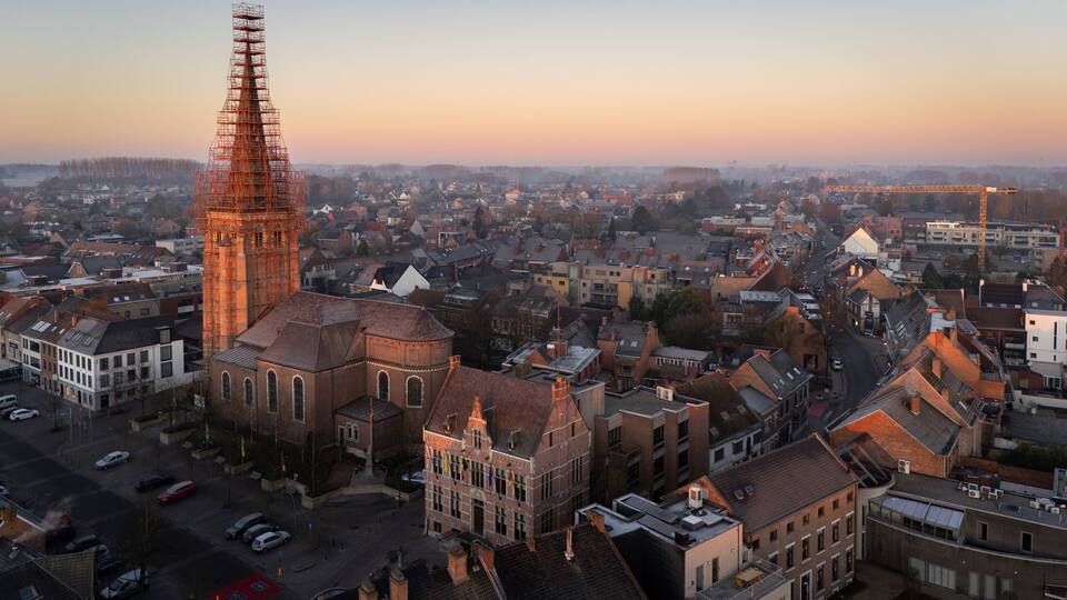 A cityscape with a prominent church tower and a construction crane.
