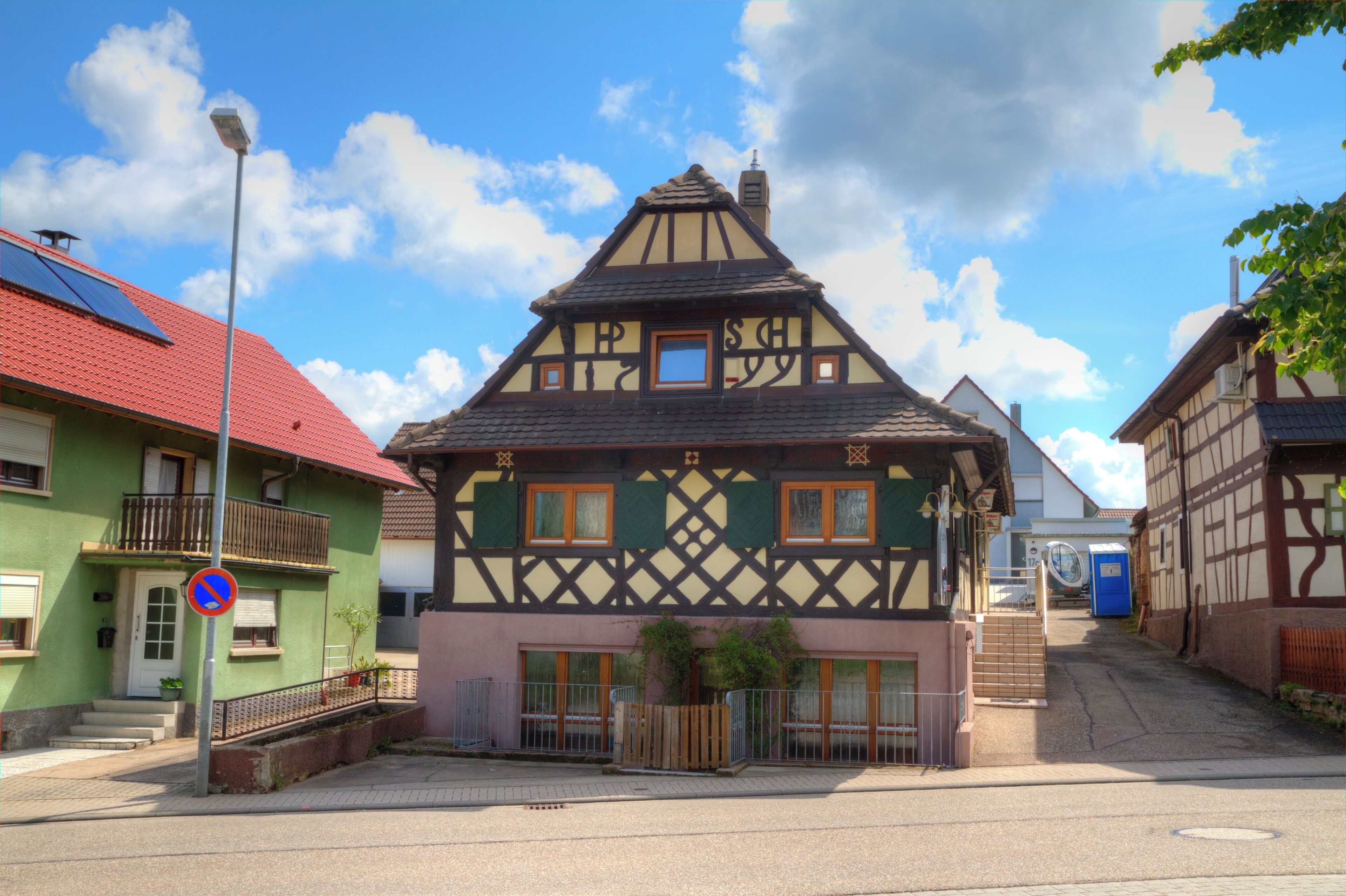 A traditional half-timbered house with a red roof, a blue door, and a small window.