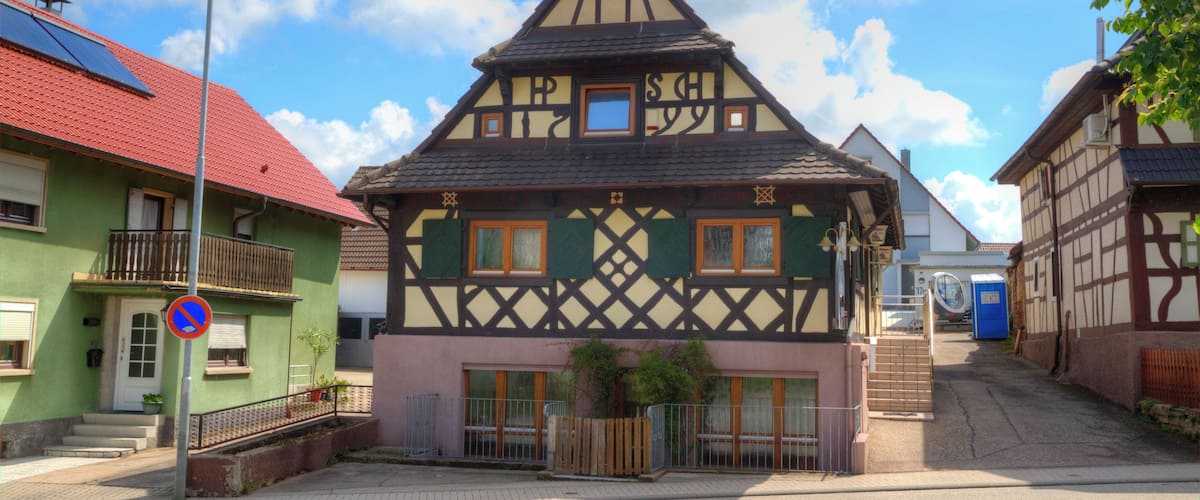 A traditional half-timbered house with a red roof, a blue door, and a small window.