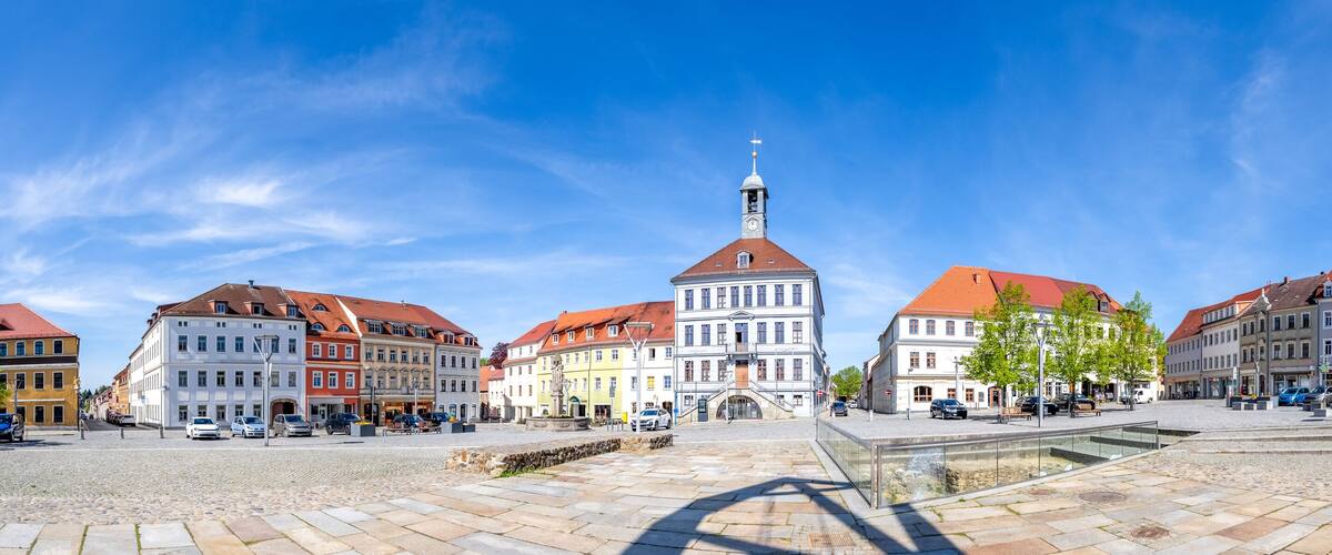 A cobblestone square with historic buildings, a clock tower, and a fountain.