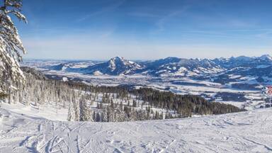A snowy mountain landscape with skiers and a ski lift.