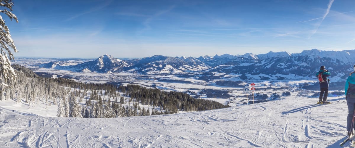 A snowy mountain landscape with skiers and a ski lift.