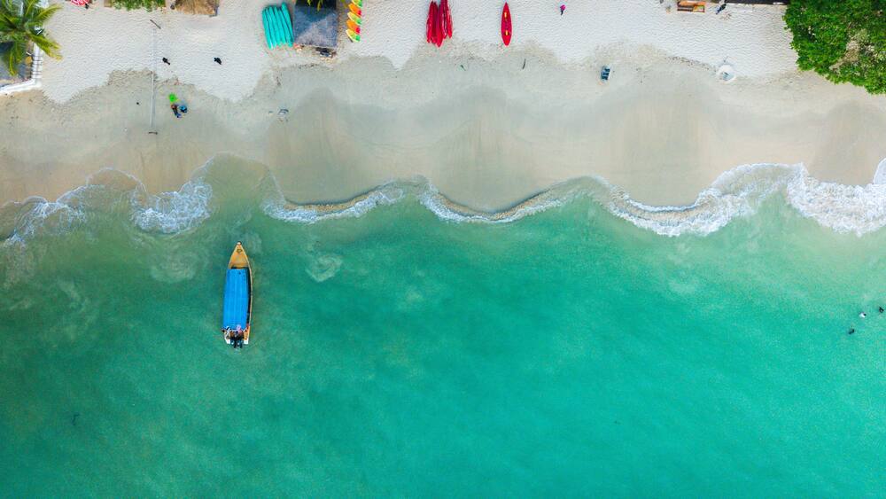 A turquoise beach with a kayak and a small boat.