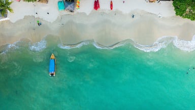 Uma praia turquesa com um caiaque e um barco pequeno.