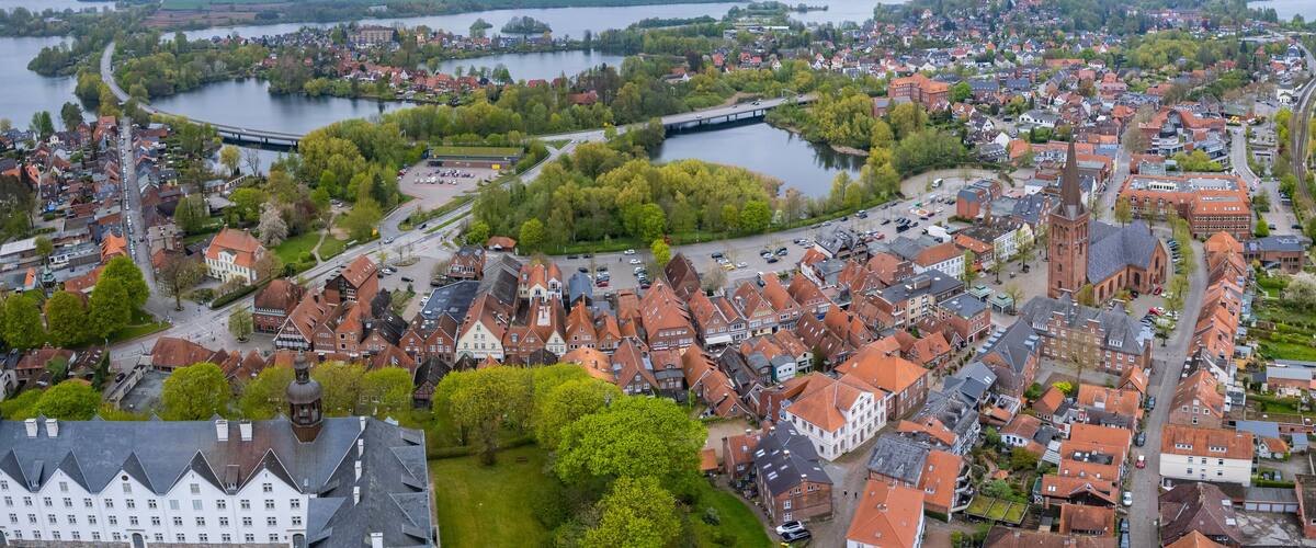 An aerial view of a riverside town with historic buildings, a church, and a bridge.