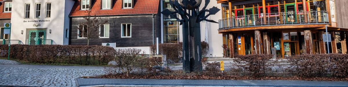 A building with a red roof, a tree sculpture, and a balcony with colorful railings.