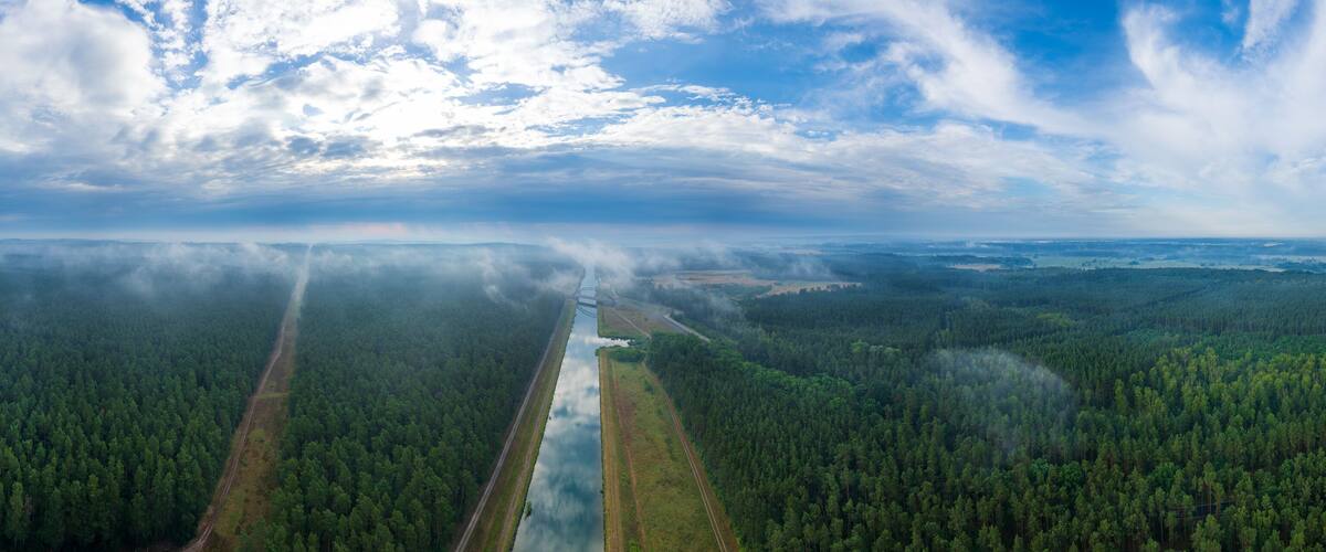 A forested landscape with a river and a railway track.