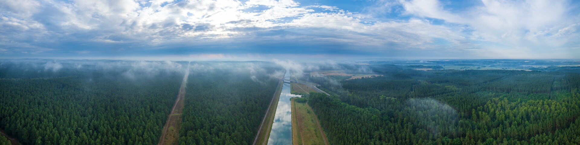 A forested landscape with a river and a railway track.