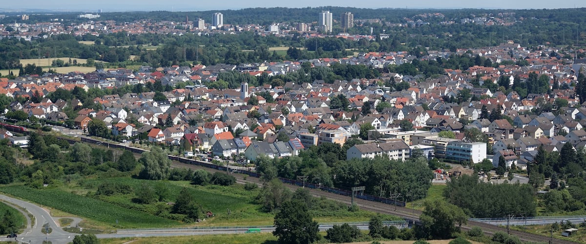 A densely populated urban area with residential buildings, a railway line, and green spaces.