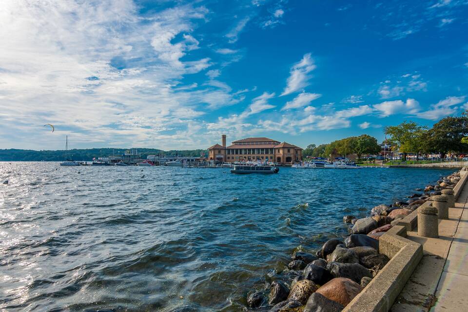 Un paisaje marítimo con barcos, un edificio grande y un muro de piedra.