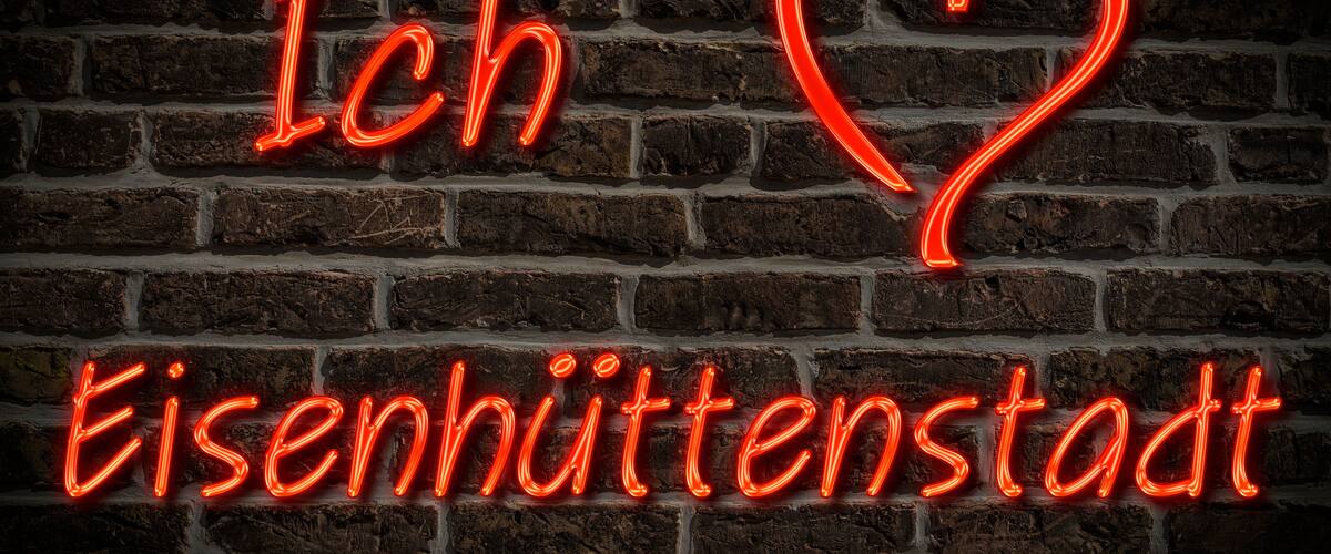 A neon sign on a brick wall with the text "Ich ♥ Eisenhuttenstadt".