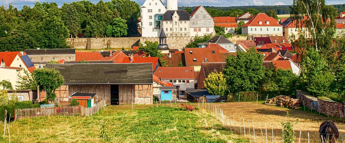 A historic town with a prominent white church, red-roofed houses, and lush greenery.