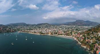 A coastal city with a bay, numerous sailboats, and a mountainous backdrop.