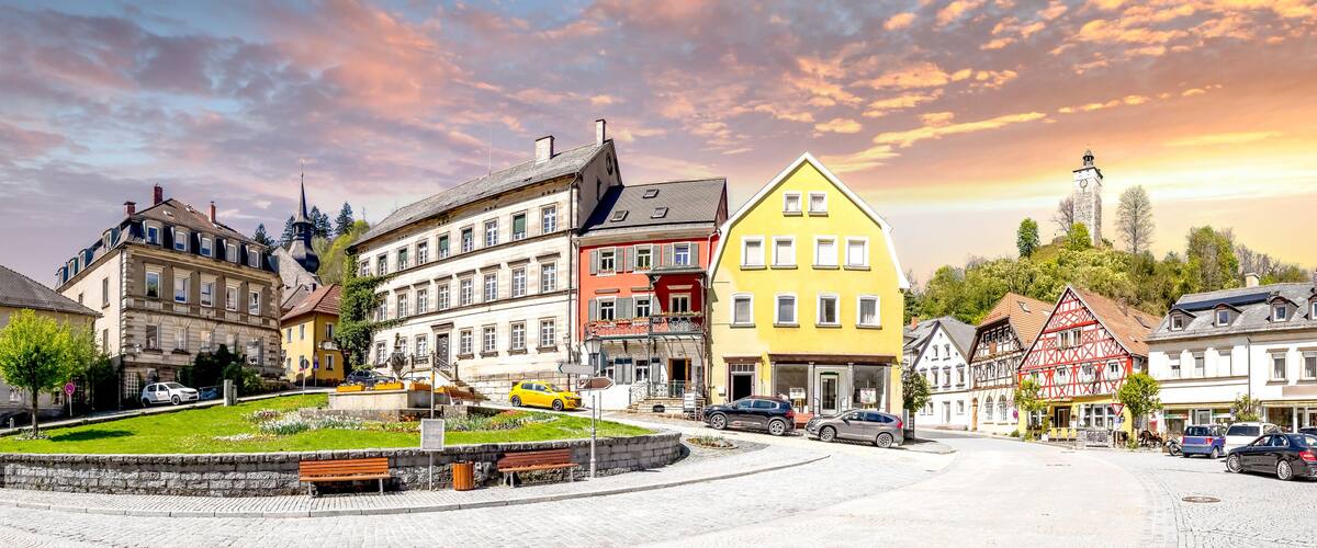 A cobblestone square with historic buildings, a church steeple, and a clock tower.