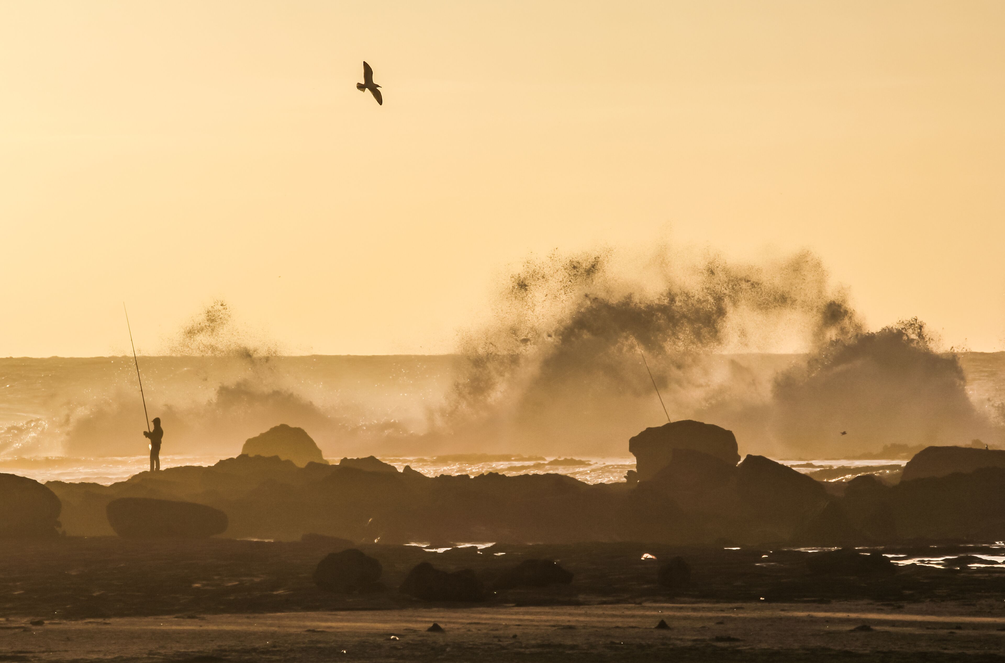 Angler mit hoch sprühender Gischt an Felsküste, Marokko