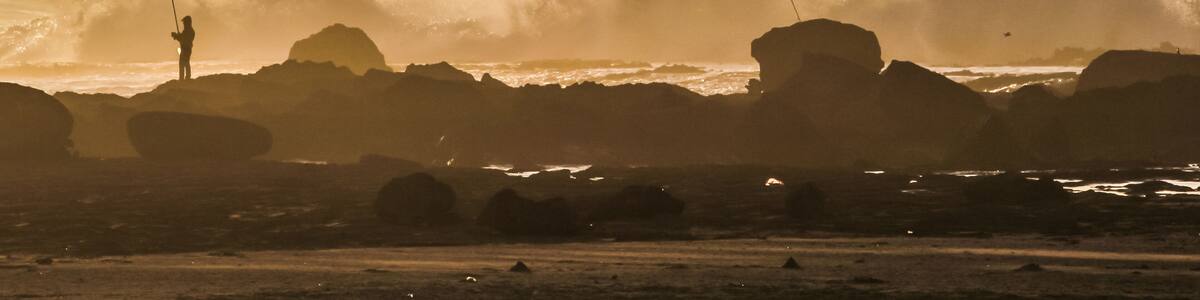 Angler mit hoch sprühender Gischt an Felsküste, Marokko