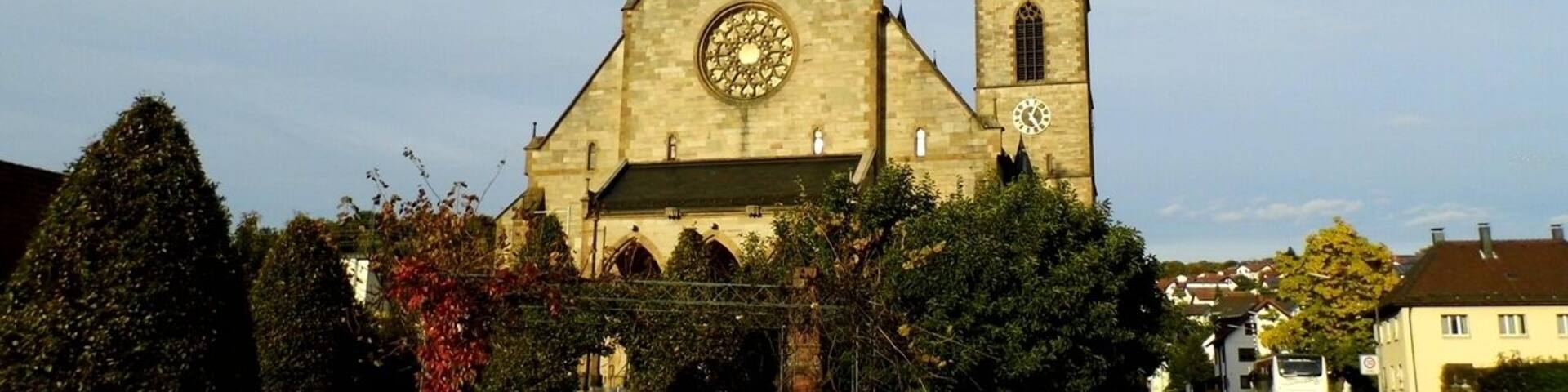 A church with a clock tower and a red bench in front.