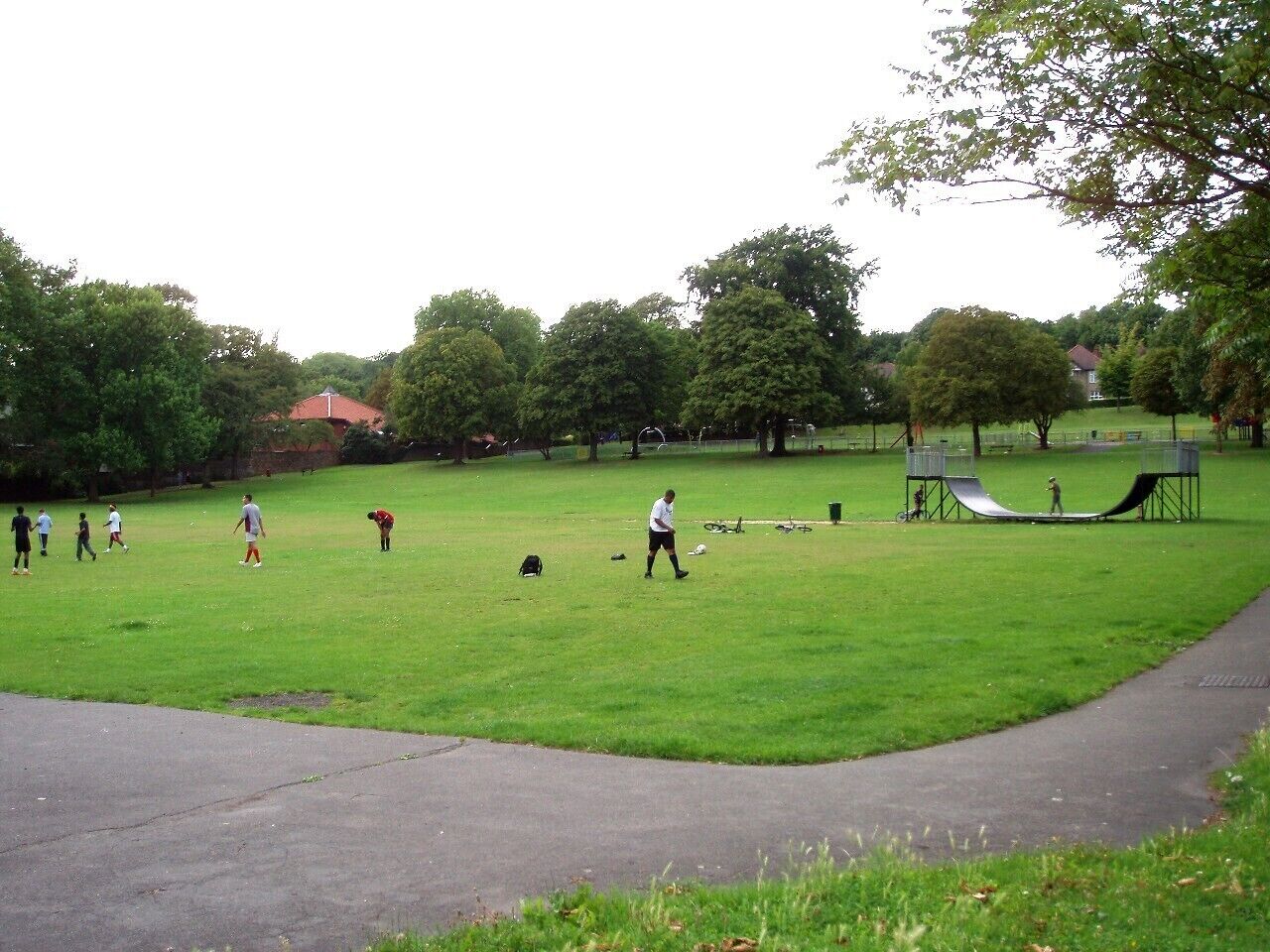 A park with a grassy field, a playground, and a walking path.