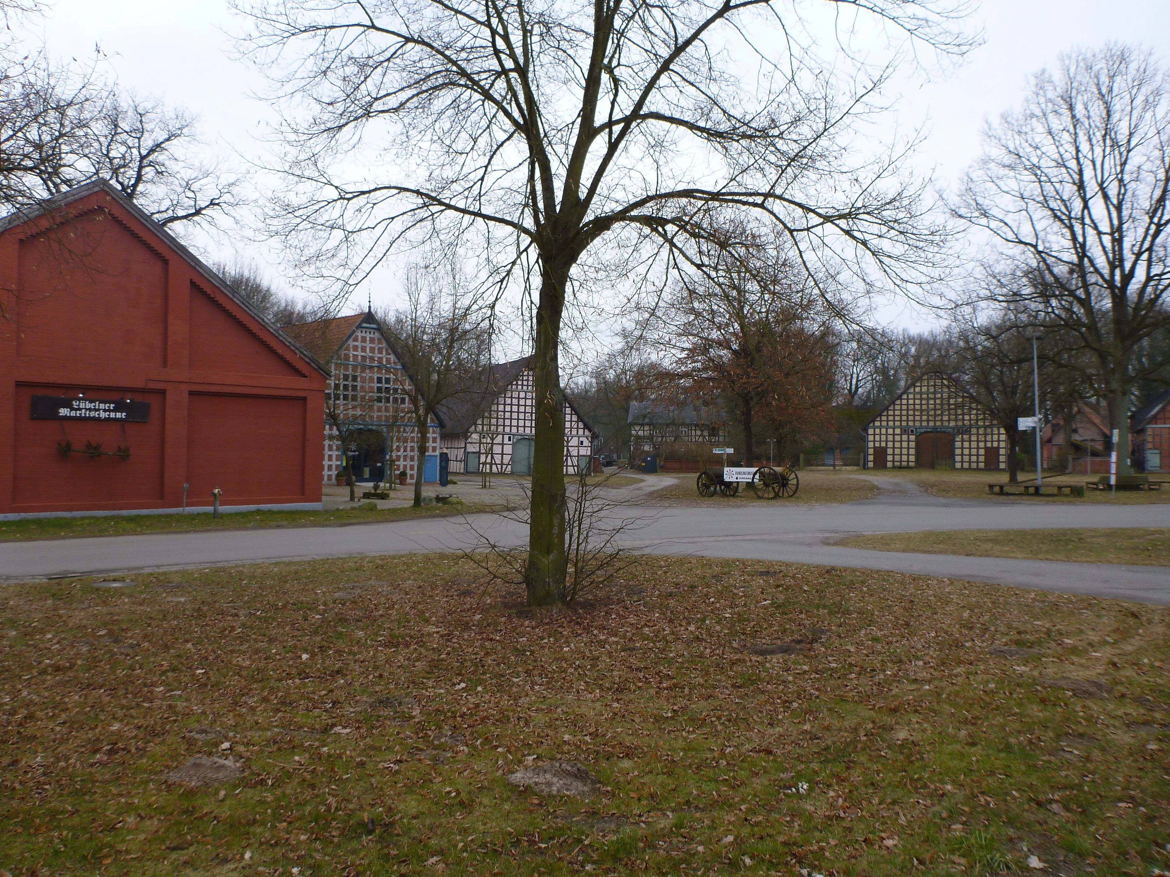 A rural village with traditional half-timbered houses, a red barn, and a tree in the foreground.
