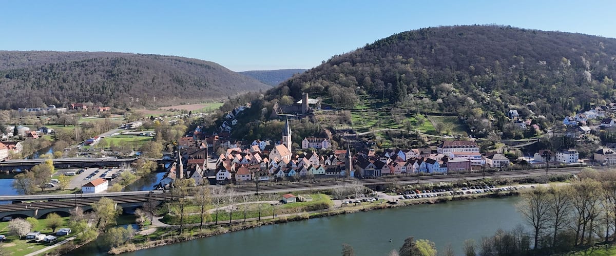 A riverside town with historic buildings, a bridge, and a hill with a church.