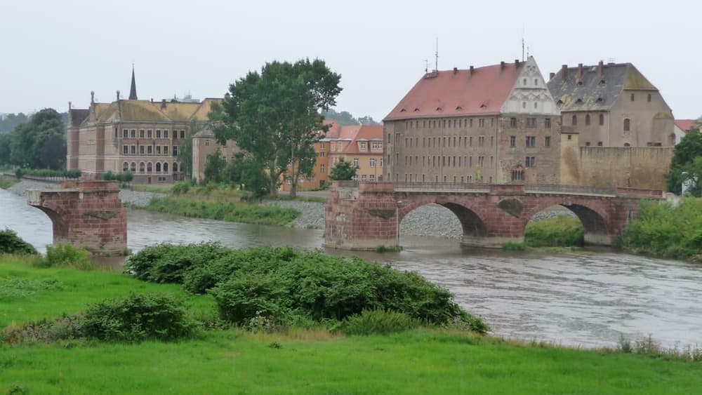 A stone bridge over a river with historic buildings on either side.