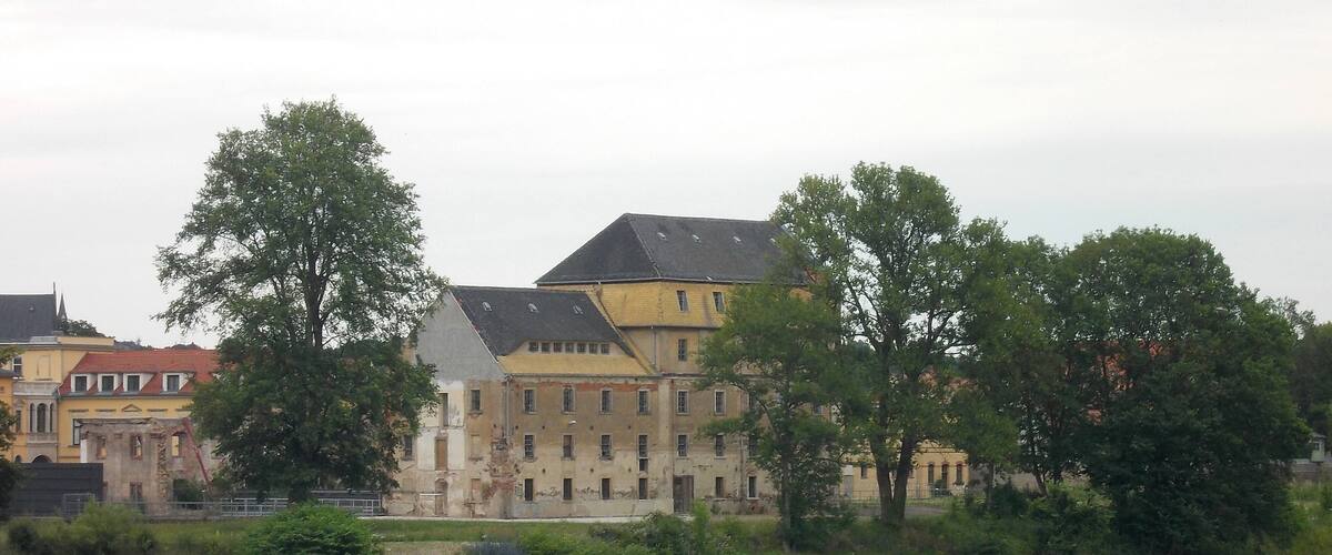 A historic building with a river in the foreground.