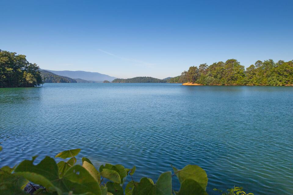 Un llac tranquil envoltat de boscos densos i muntanyes allunyades.