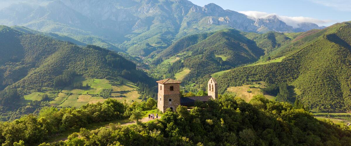 A mountainous landscape with a stone tower and a church.