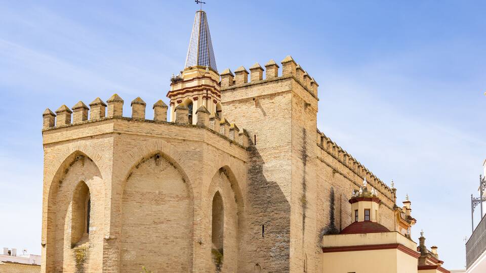A historic stone building with arched windows and a pointed tower.