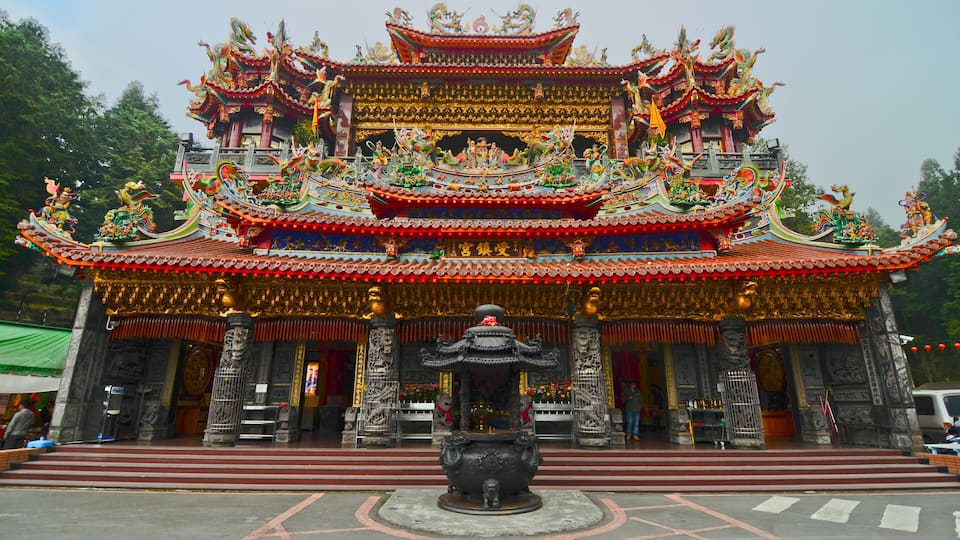 A traditional multi-tiered temple with ornate decorations and a central statue.