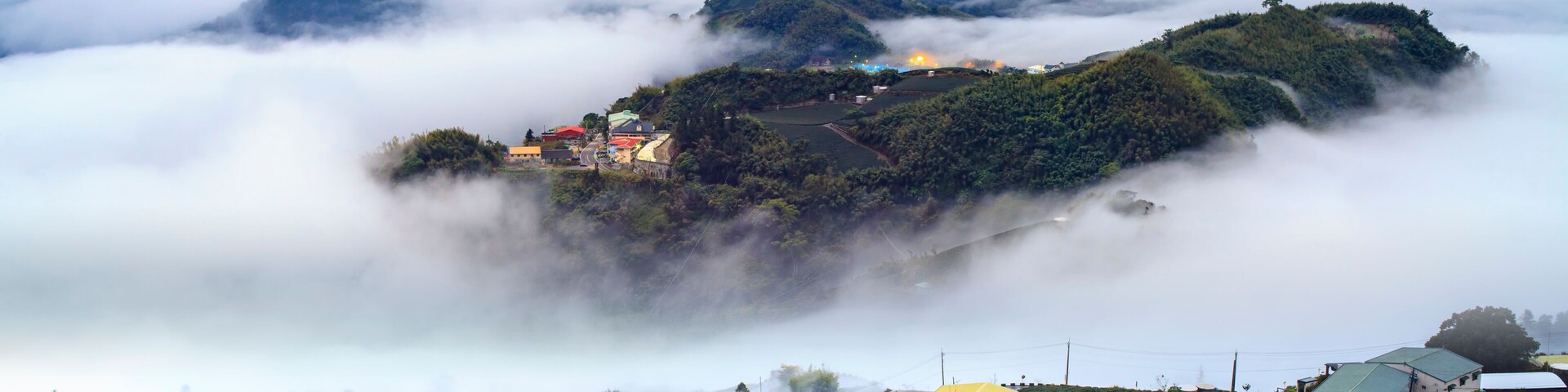 Un pueblo montañoso cubierto de niebla, con campos de té en terrazas y casas acurrucadas entre las nubes.