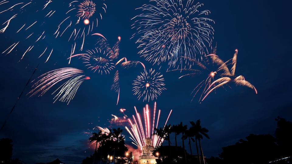 Vuurwerk boven een standbeeld in de nacht.