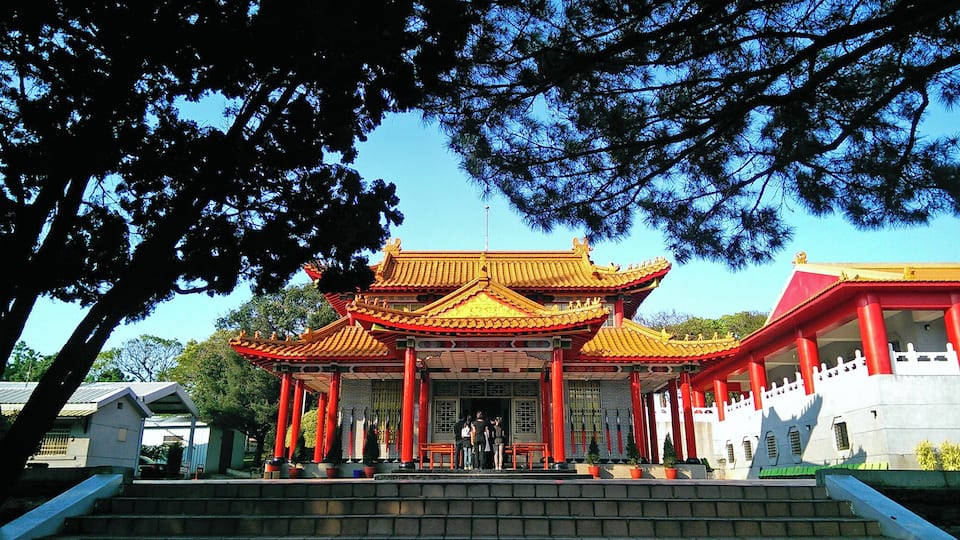 Een traditioneel Chinees gebouw met rode zuilen en gouden daken.