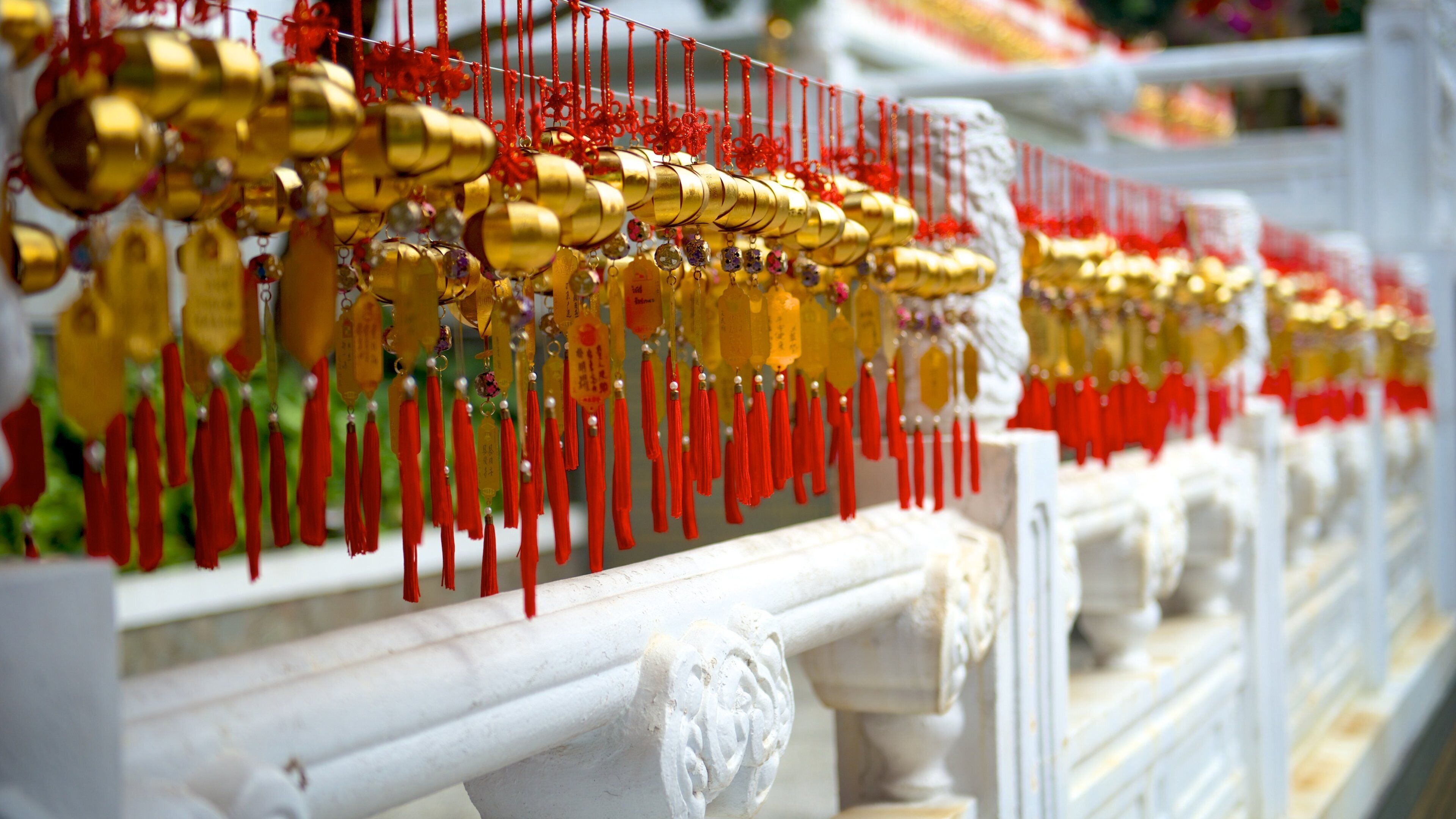 A row of golden and red decorations hanging on a white balustrade.