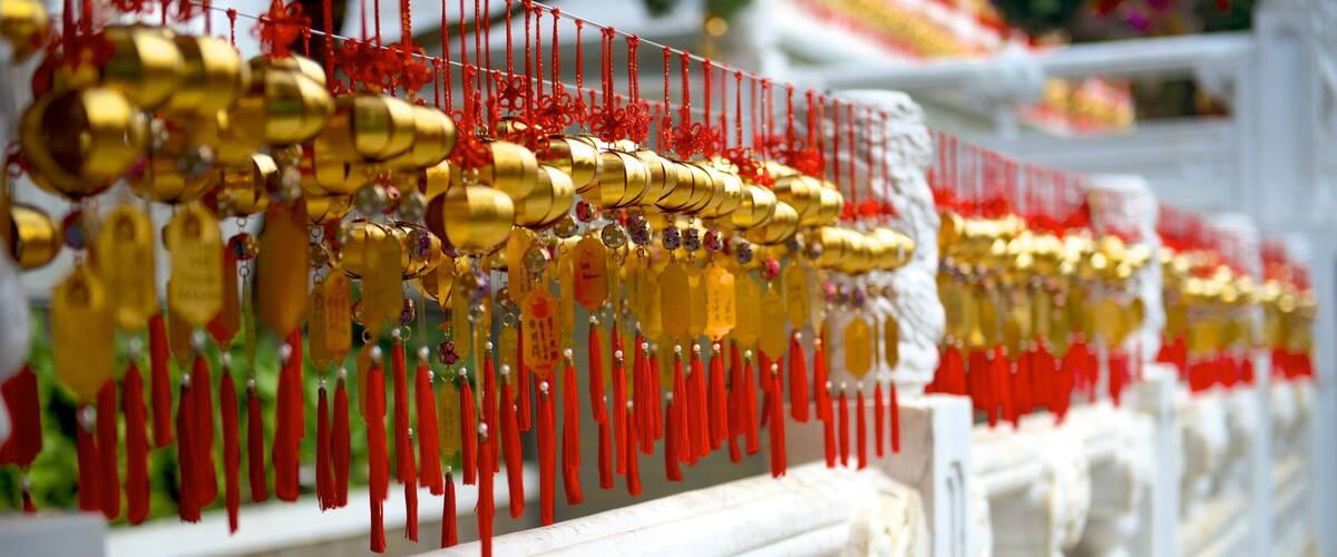 A row of golden and red decorations hanging on a white balustrade.