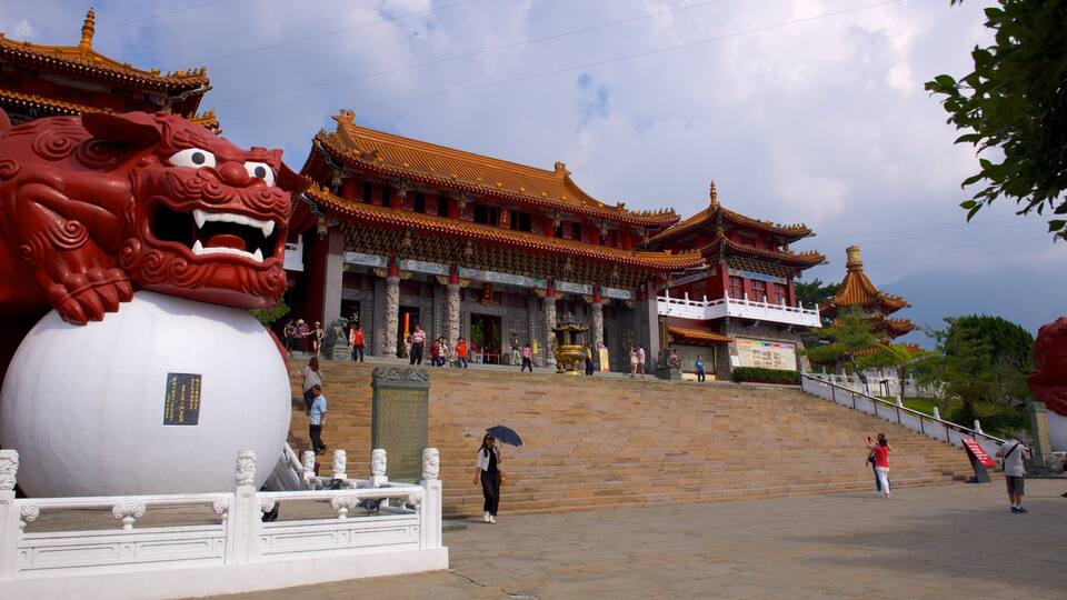 A traditional Chinese temple with ornate architecture, large red lion statues, and a stone inscription.