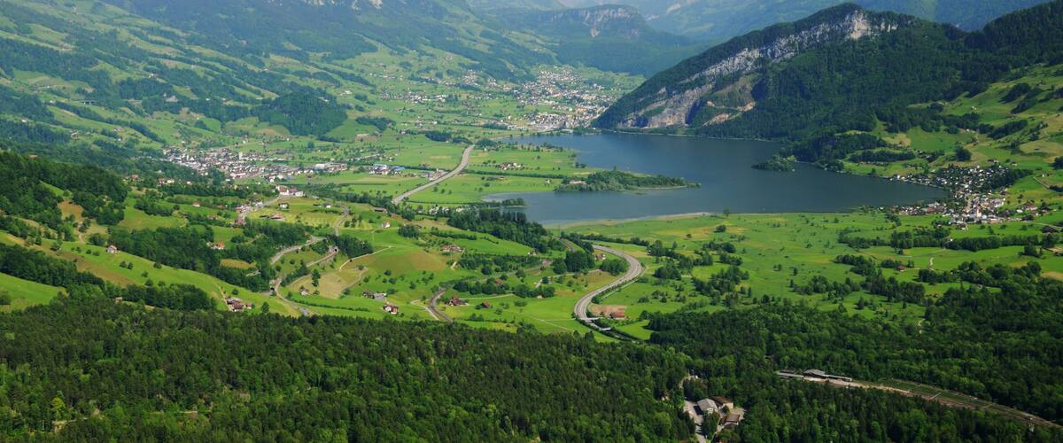A mountainous landscape with a lake, winding roads, and scattered buildings.