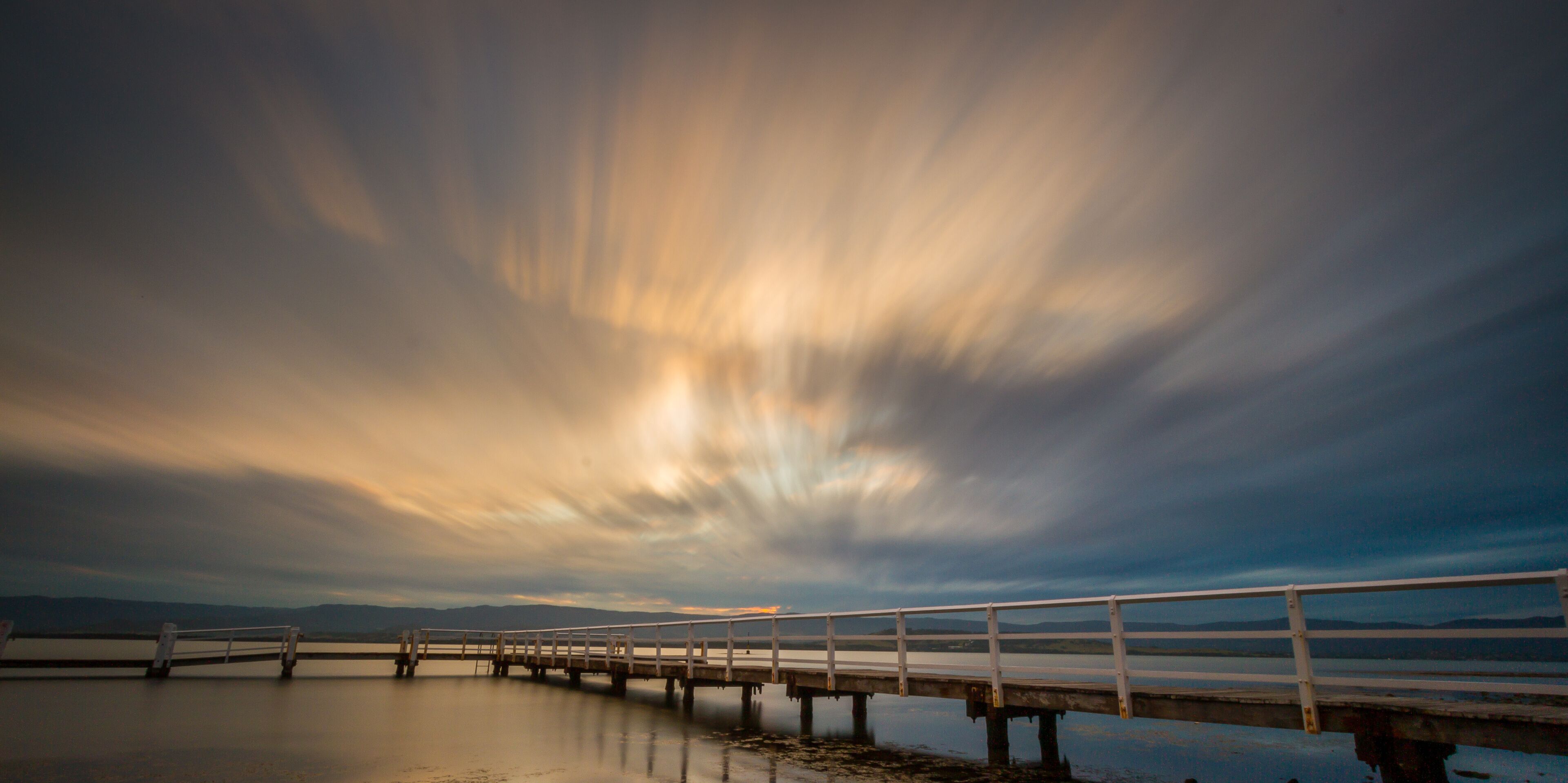 Dramatic sky over a wooden jetty on Lake Illawarra, Shellharbour Area, Wollongong, New South Wales, Australia