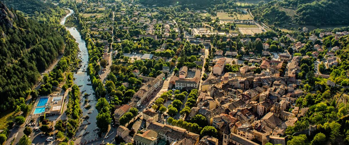 A town nestled in a valley with a river, surrounded by mountains.