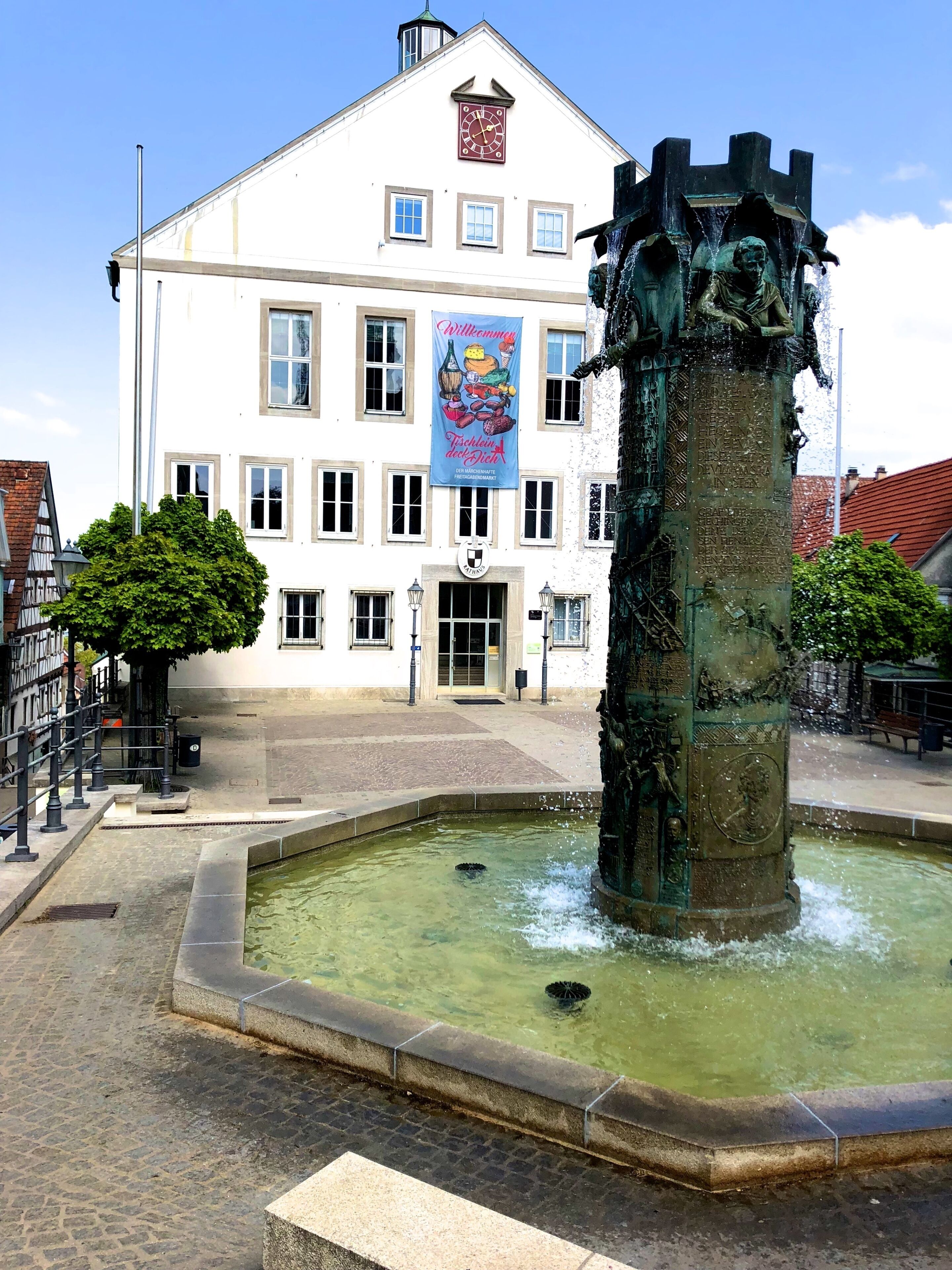 A historic building with a clock and a fountain in front.