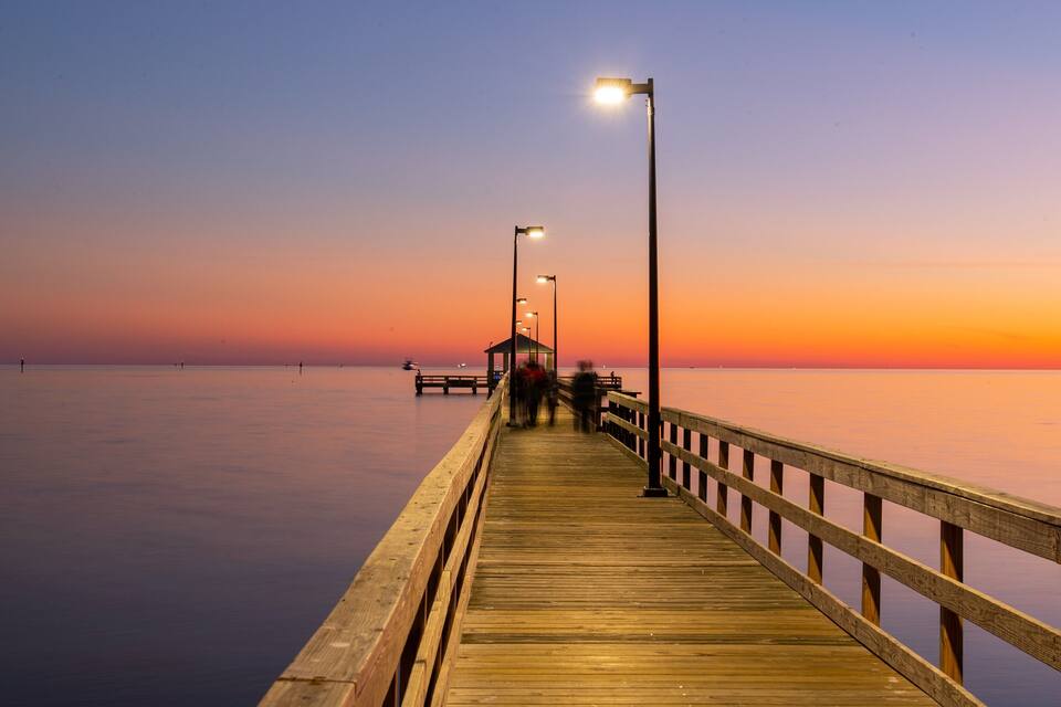A wooden pier extending into calm waters at sunset.