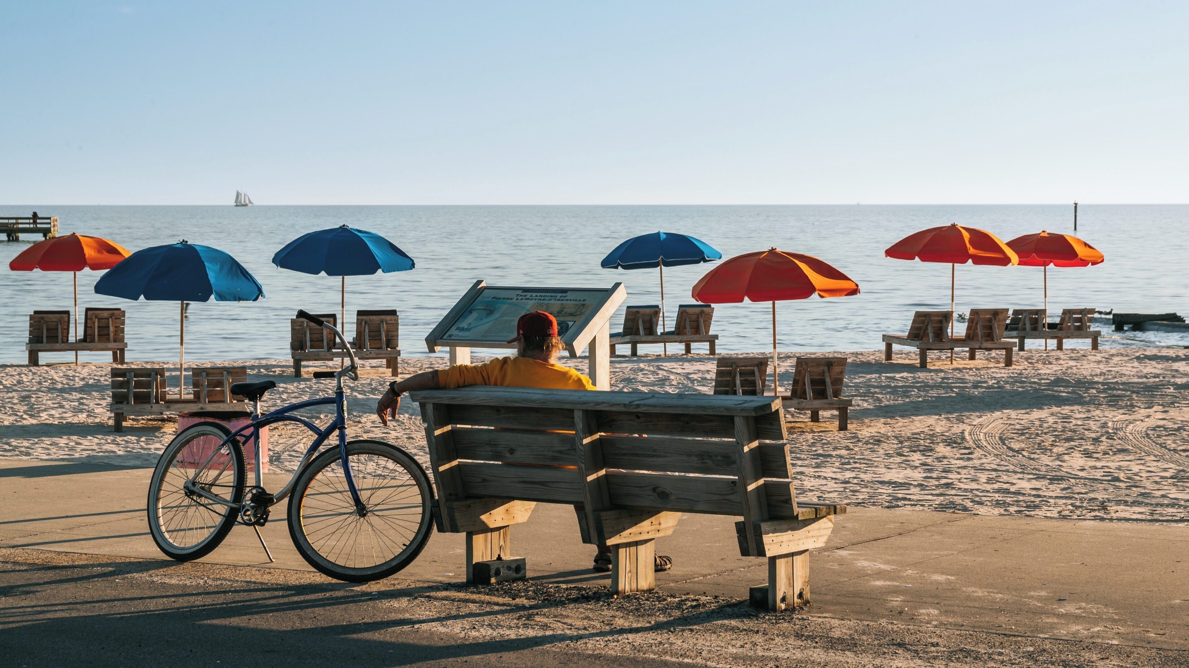 Relaxing at Biloxi Beach under colorful umbrellas with a view of the gulf coast and a serene atmosphere at sunset