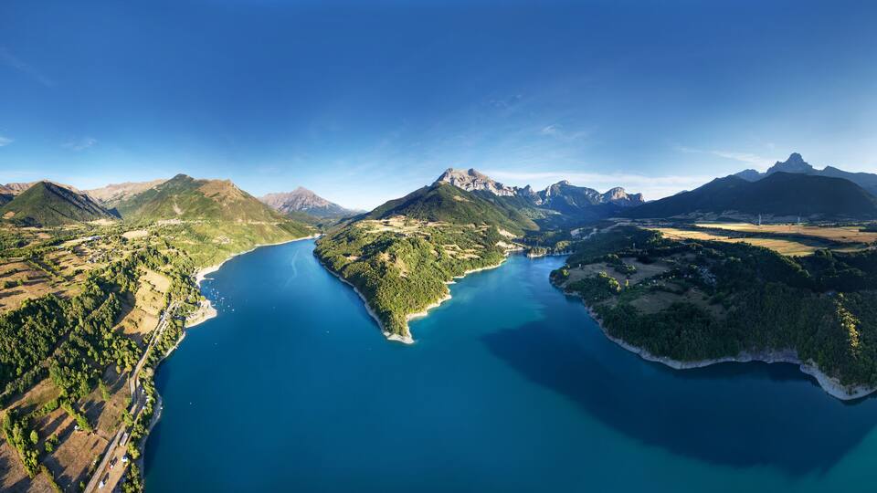 A mountainous landscape with a large lake surrounded by forested areas and a small island.