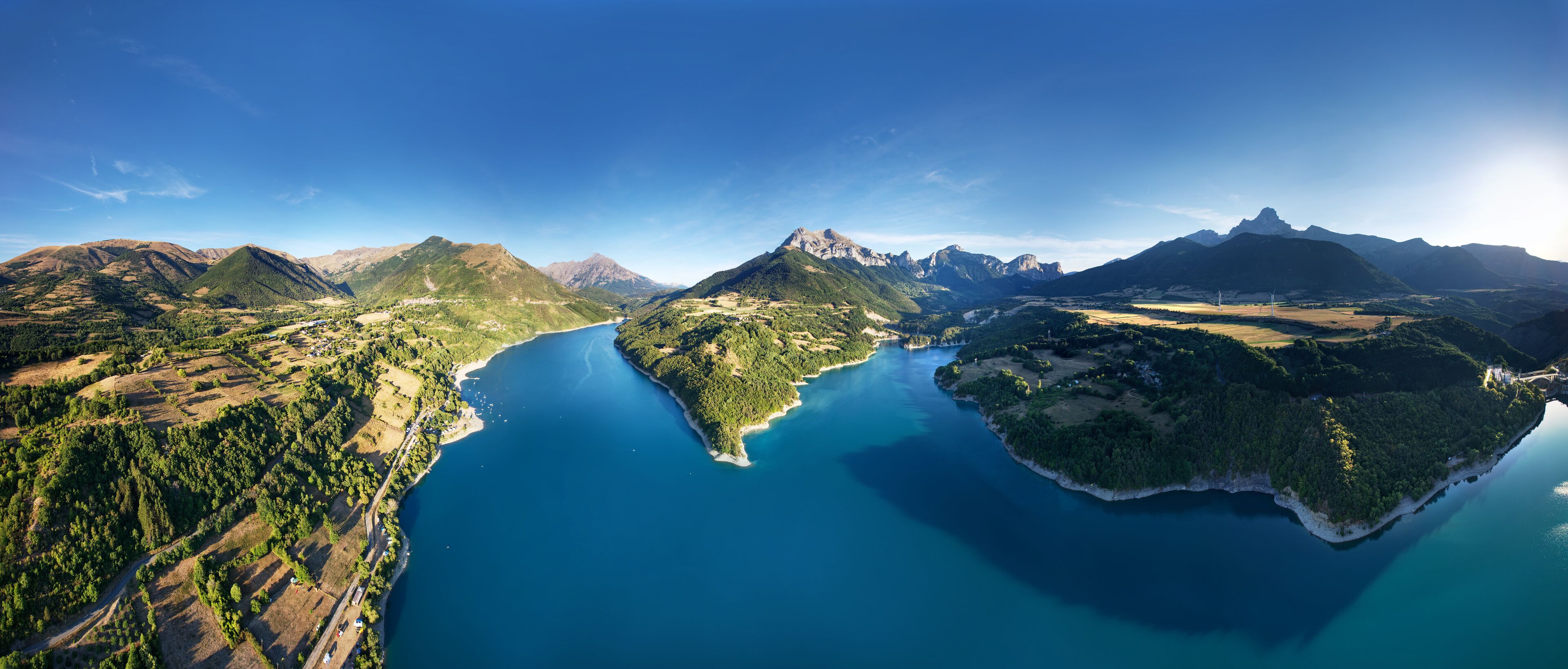 A mountainous landscape with a large lake surrounded by forested areas and a small island.