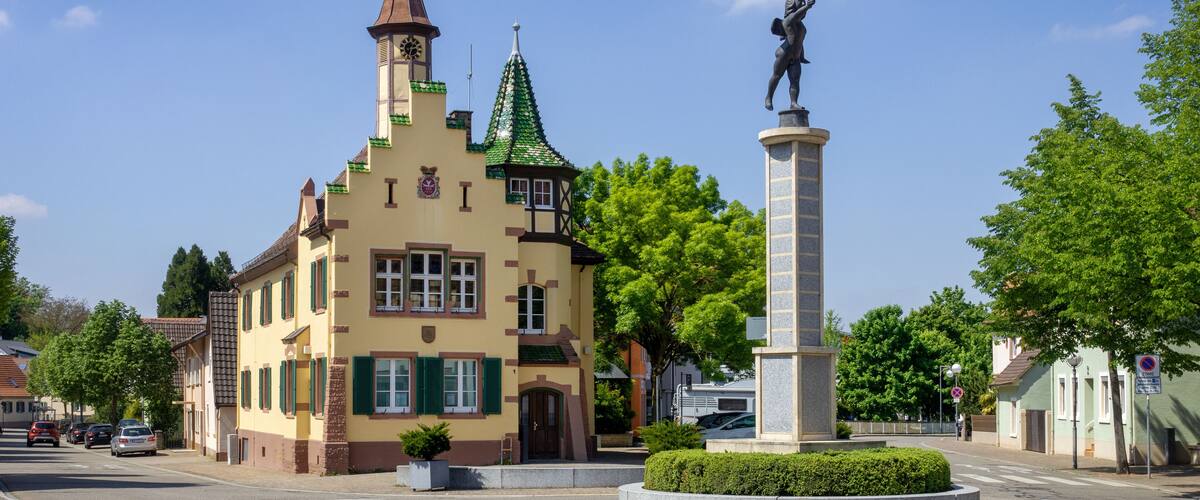 A historic building with a tower and a statue in front.