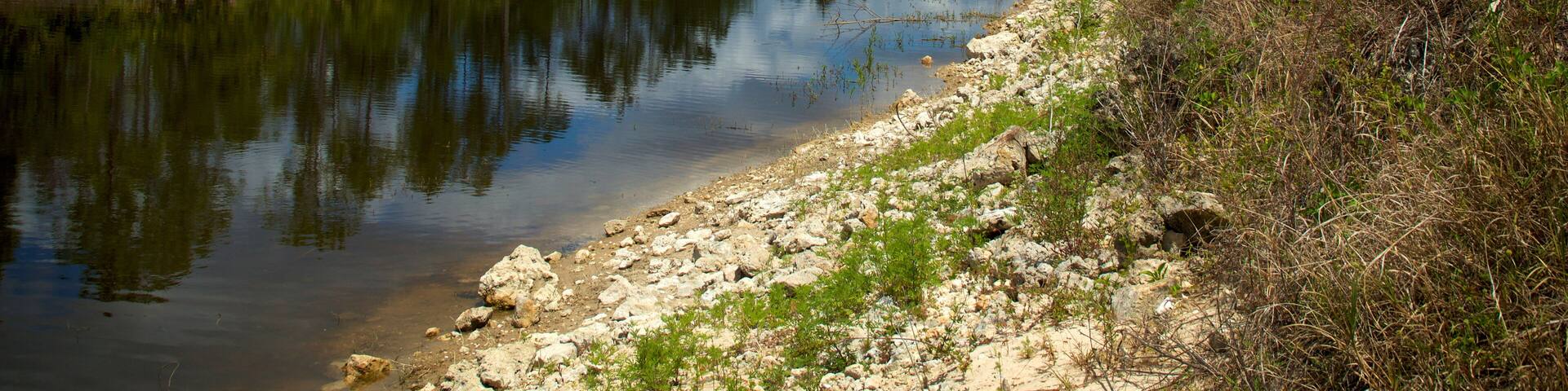 Beautiful scenic view of the great cypress basin canal in Golden Gate area of Naples Florida, showing clear clean water, cloudy sky and trees on the banks.
